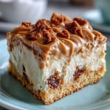 Decadent Baked Biscoff Cake with Creamy Lotus Frosting on a rustic plate, ready to be sliced and served alongside a hot cup of coffee.