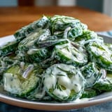 A refreshing summer salad featuring sliced cucumbers and red onion in a creamy dill dressing, perfect for picnics.  
