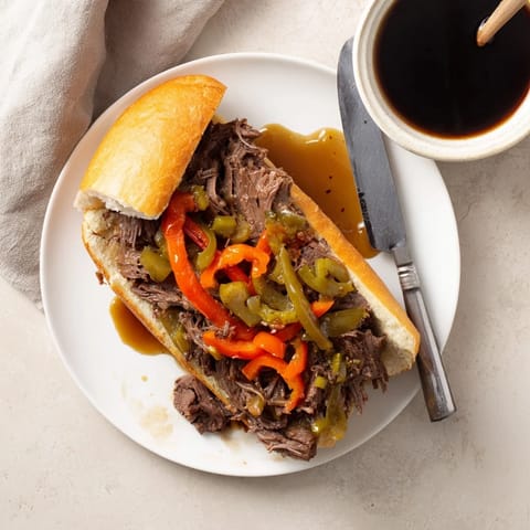 A Chicago-style Italian Beef Sandwich stuffed with juicy shredded beef, topped with sweet peppers and extra au jus.