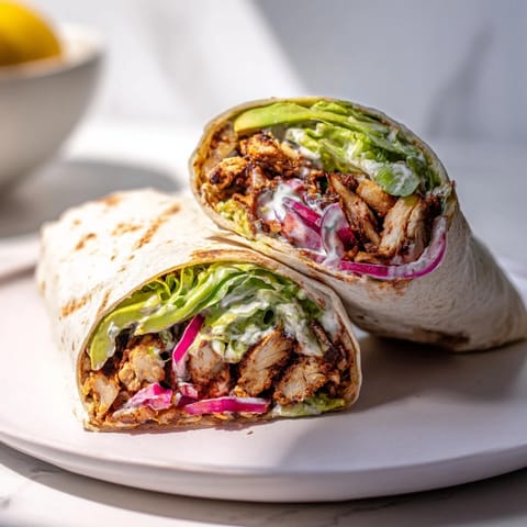 Tangy Greek yogurt sauce drizzled over a vibrant smoky chipotle chicken wrap filled with fresh vegetables.  