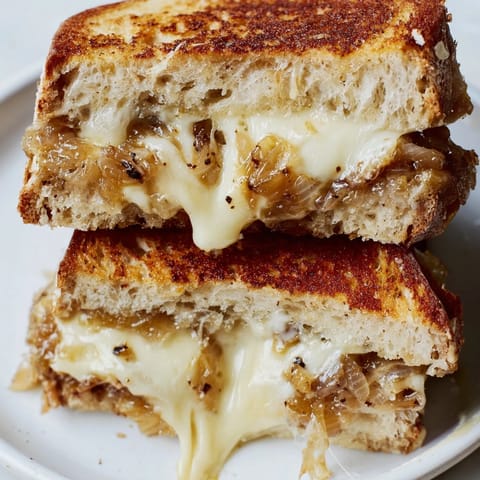 Slices of crispy, golden-brown Caramelized Onion Grilled Cheese reveal layers of jammy onions and melted sharp white cheddar.  
