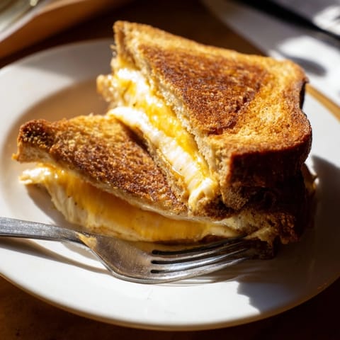 Freshly grilled Triple Cheese Sourdough Grilled Cheese served hot with a side of creamy tomato soup.
