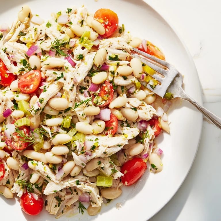 Close-up of Lemony White Bean Chicken Salad showing juicy chicken, cherry tomatoes, and a glossy lemon-herb dressing.