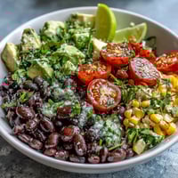 A vibrant Black Bean and Veggie Bowl with diced avocado and fresh cilantro, dressed in zesty lime vinaigrette.
